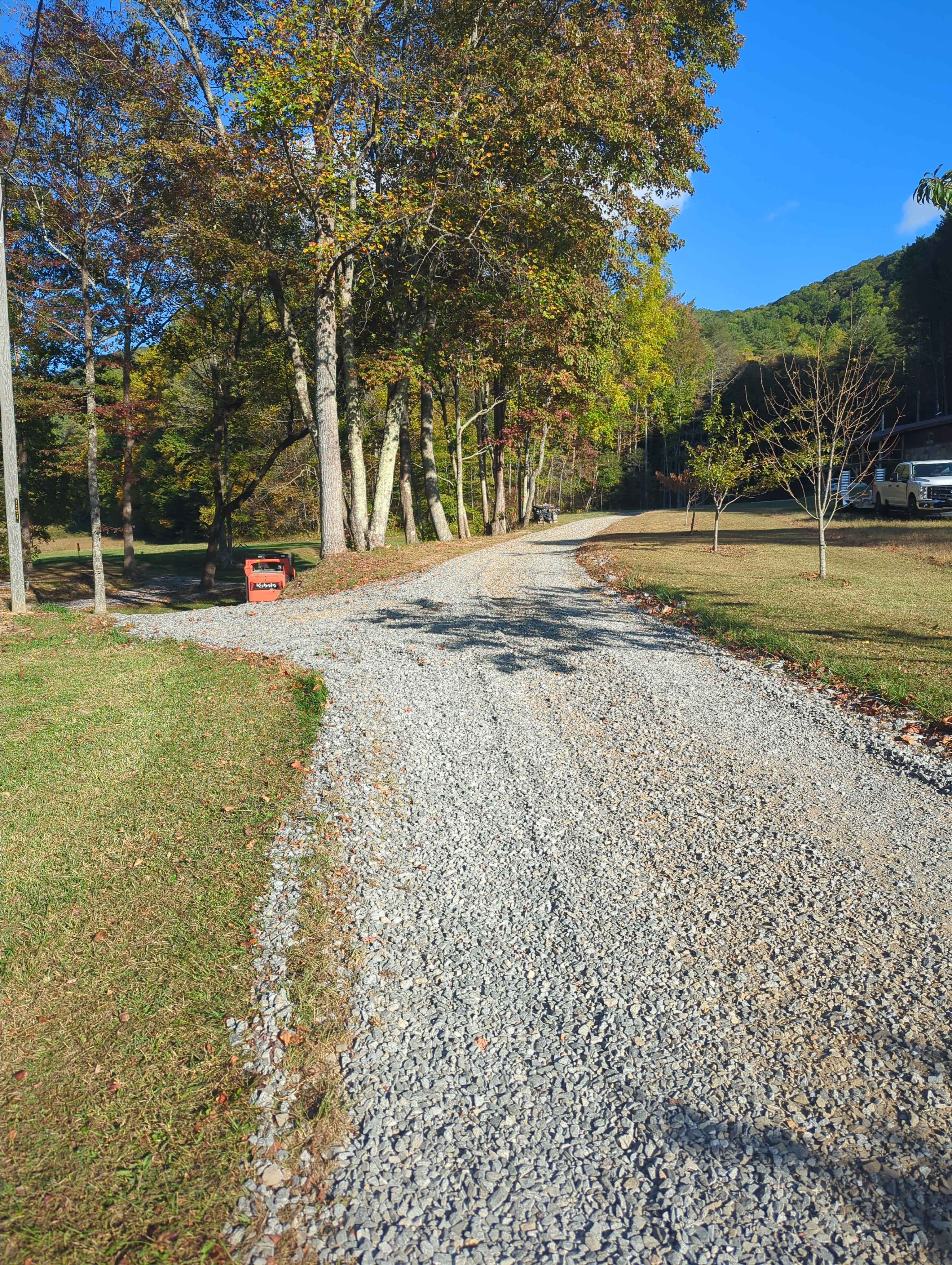 Gravel road winding through autumn trees with mountain in background