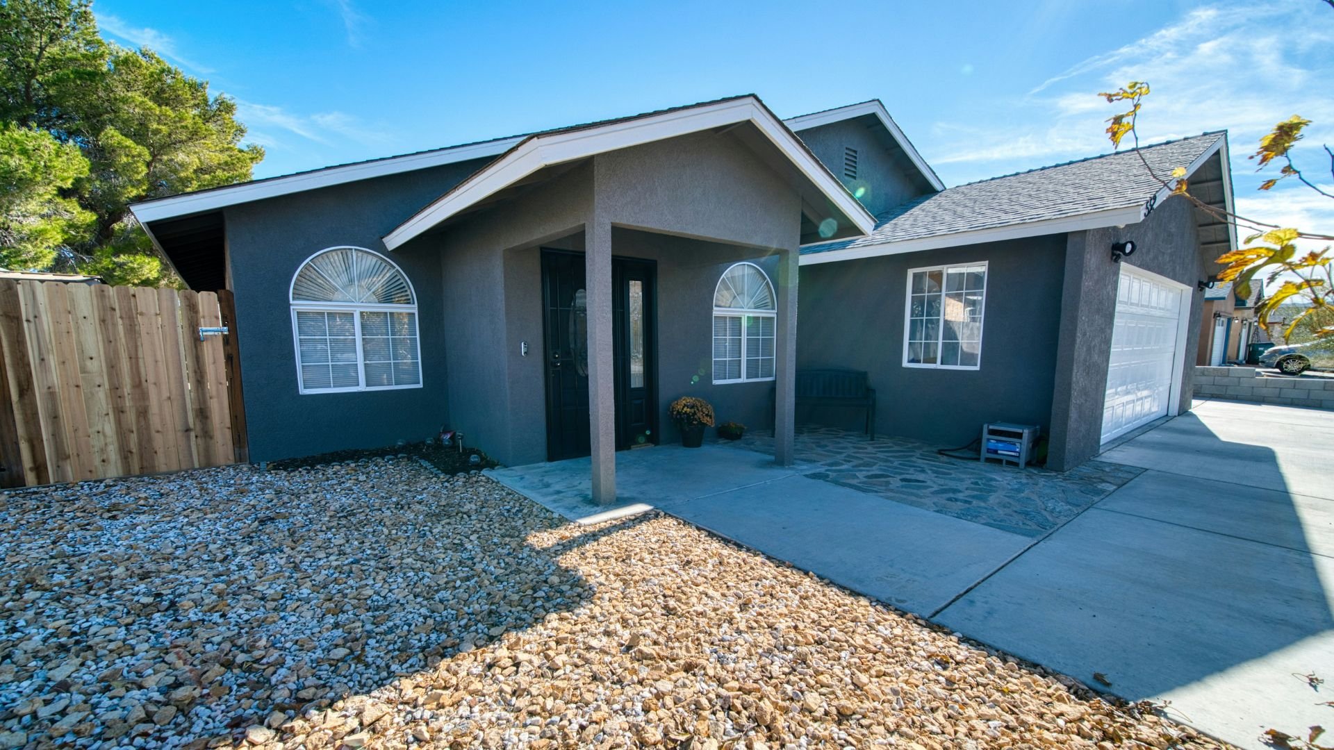 Gray single-story house with covered porch and rocky landscaping